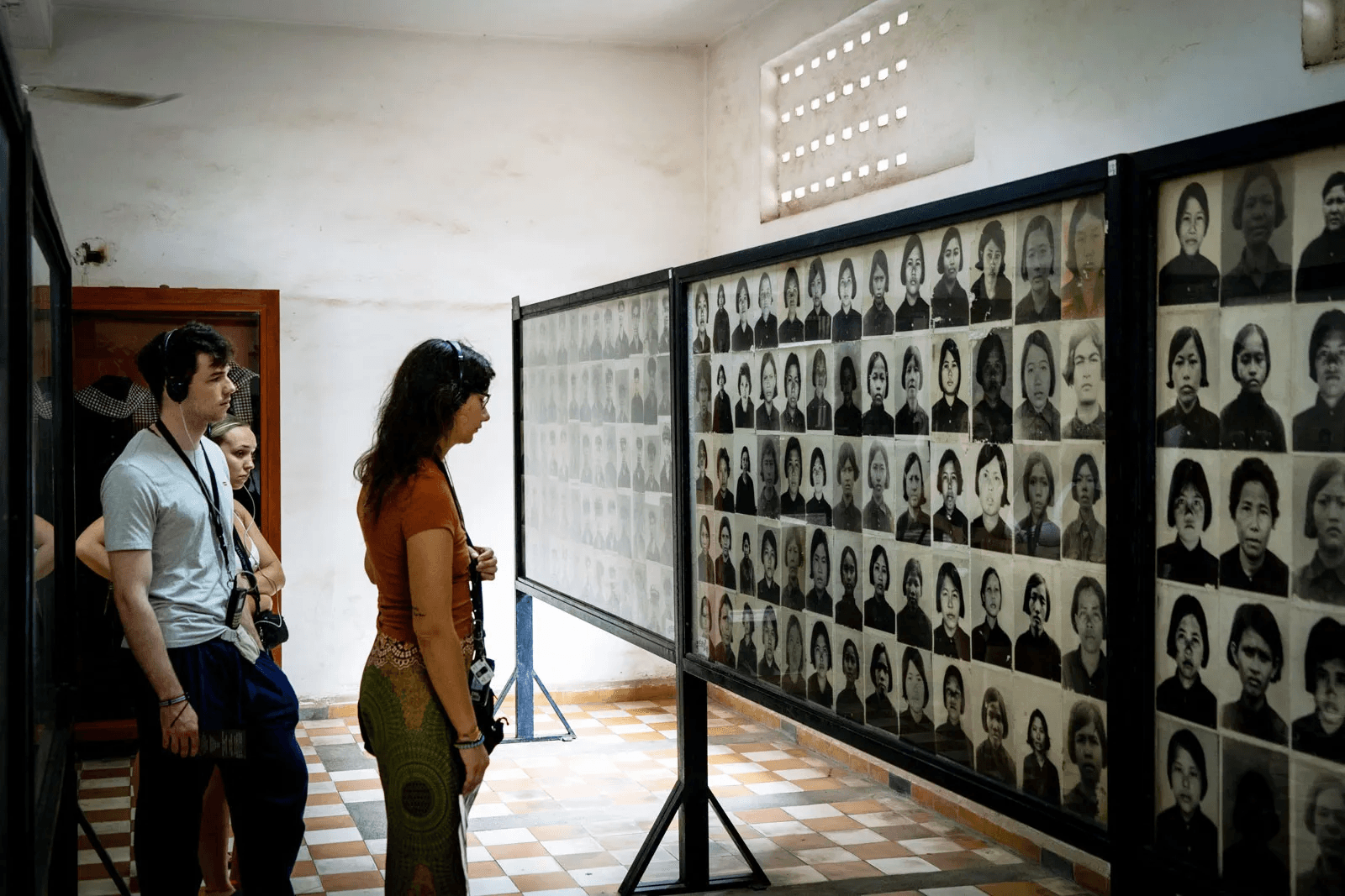 Visitors stand in solemn reflection before the portraits of victims at Tuol Sleng Genocide Museum